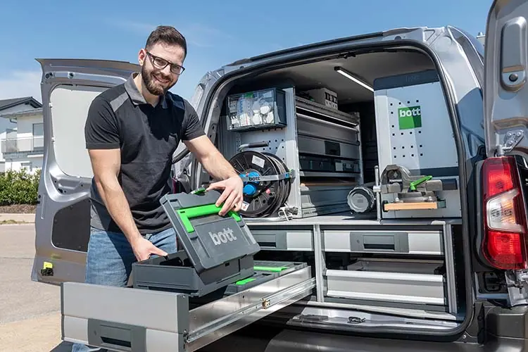 Techniker entnimmt einen bott Systainer aus dem Unterflurmodul eines Servicefahrzeugs